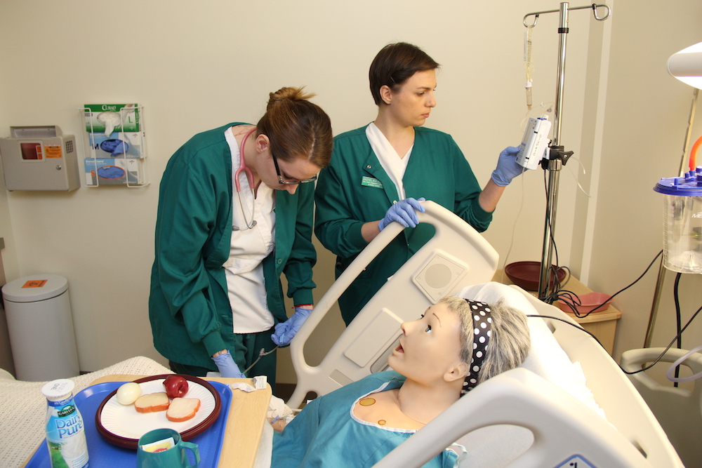 Two medical assistant students check vitals on a patient simulation